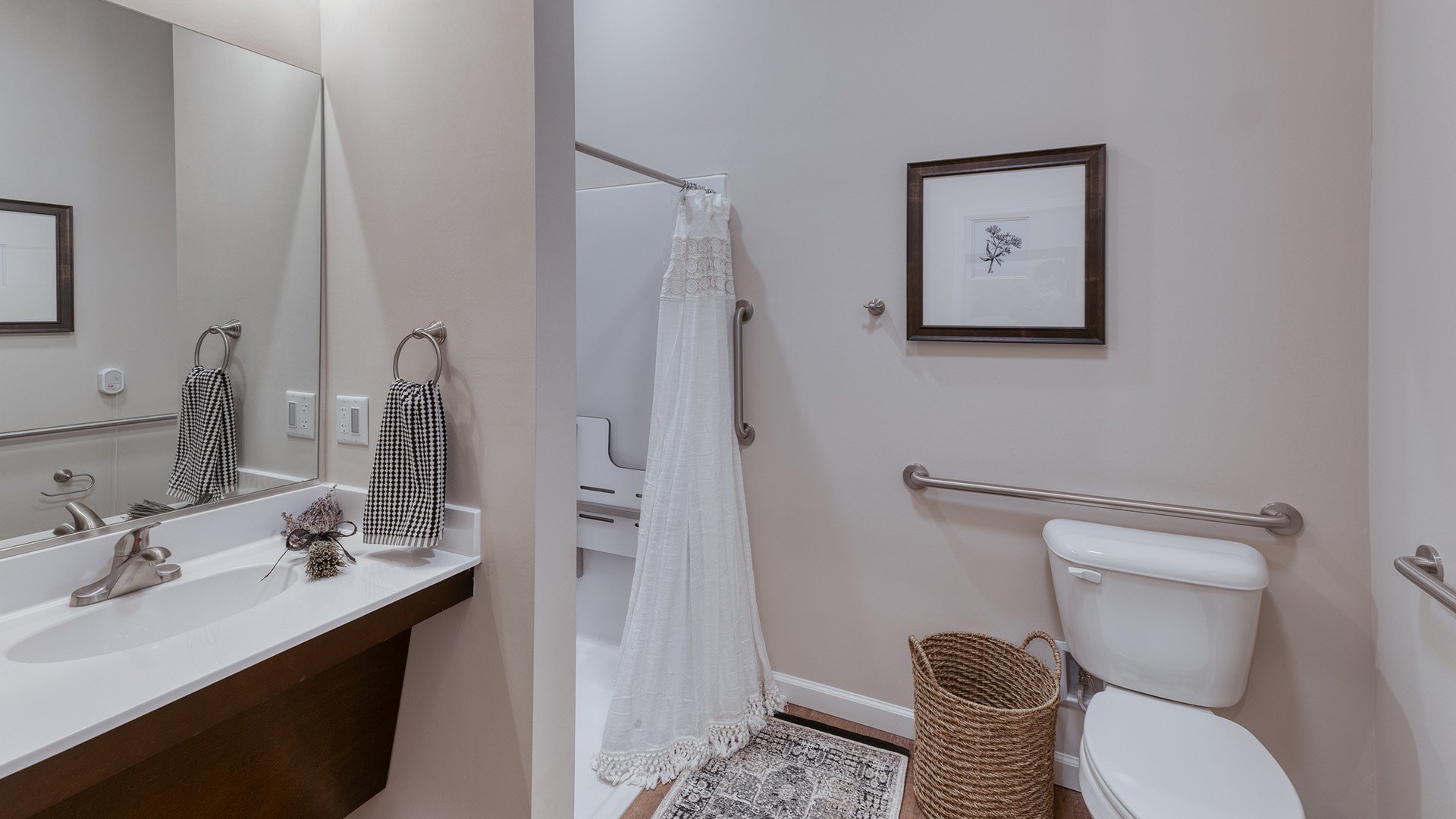 An accessible bathroom in a senior apartment at Cedarhurst of Arnold, featuring safety rails and a roll-in shower