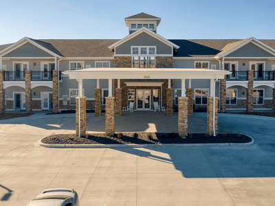 An inviting view of the Cedarhurst of Arnold senior living community from the outside, complete with the main building and its distinctive sign