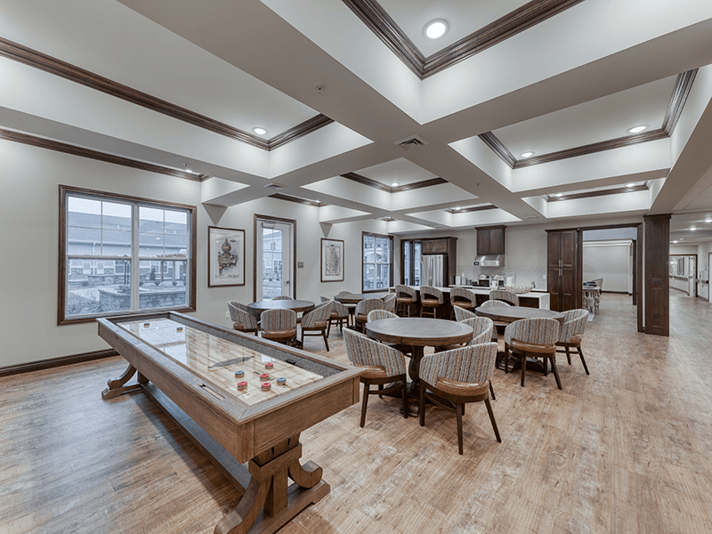 A fun-filled common area at Cedarhurst of Arnold, offering residents entertainment with game tables and a shuffleboard setup