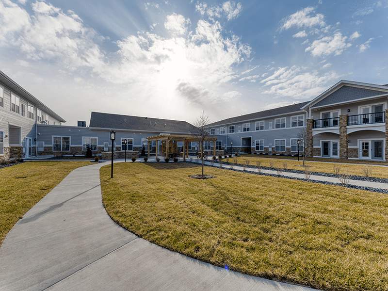 Outdoor lawn and patio area with a pergola at the Cedarhurst of Arnold senior living community