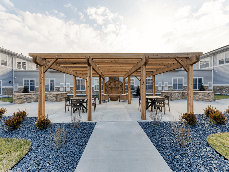 An inviting outdoor patio space with a wooden pergola at the Cedarhurst of Arnold senior living community