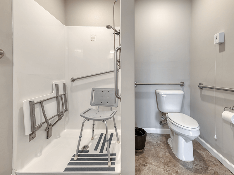 An accessible bathroom in a senior apartment at Cedarhurst of Bethalto, featuring safety rails and a roll-in shower.