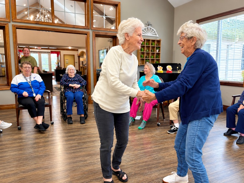 Residents dancing together as friends cheer them on at Cedarhurst of Bethalto senior living community