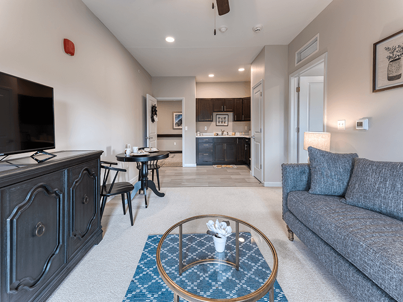 An apartment living room and kitchenette with accessible layouts and senior-friendly features at Cedarhurst of Blue Springs