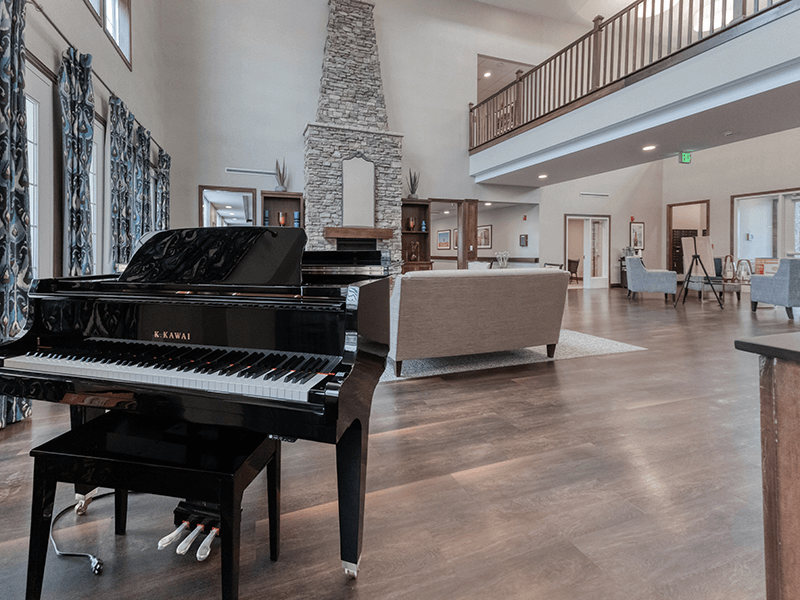 Common area at Cedarhurst of Blue Springs, offering a relaxing space with comfortable furniture and a piano for musical enrichment