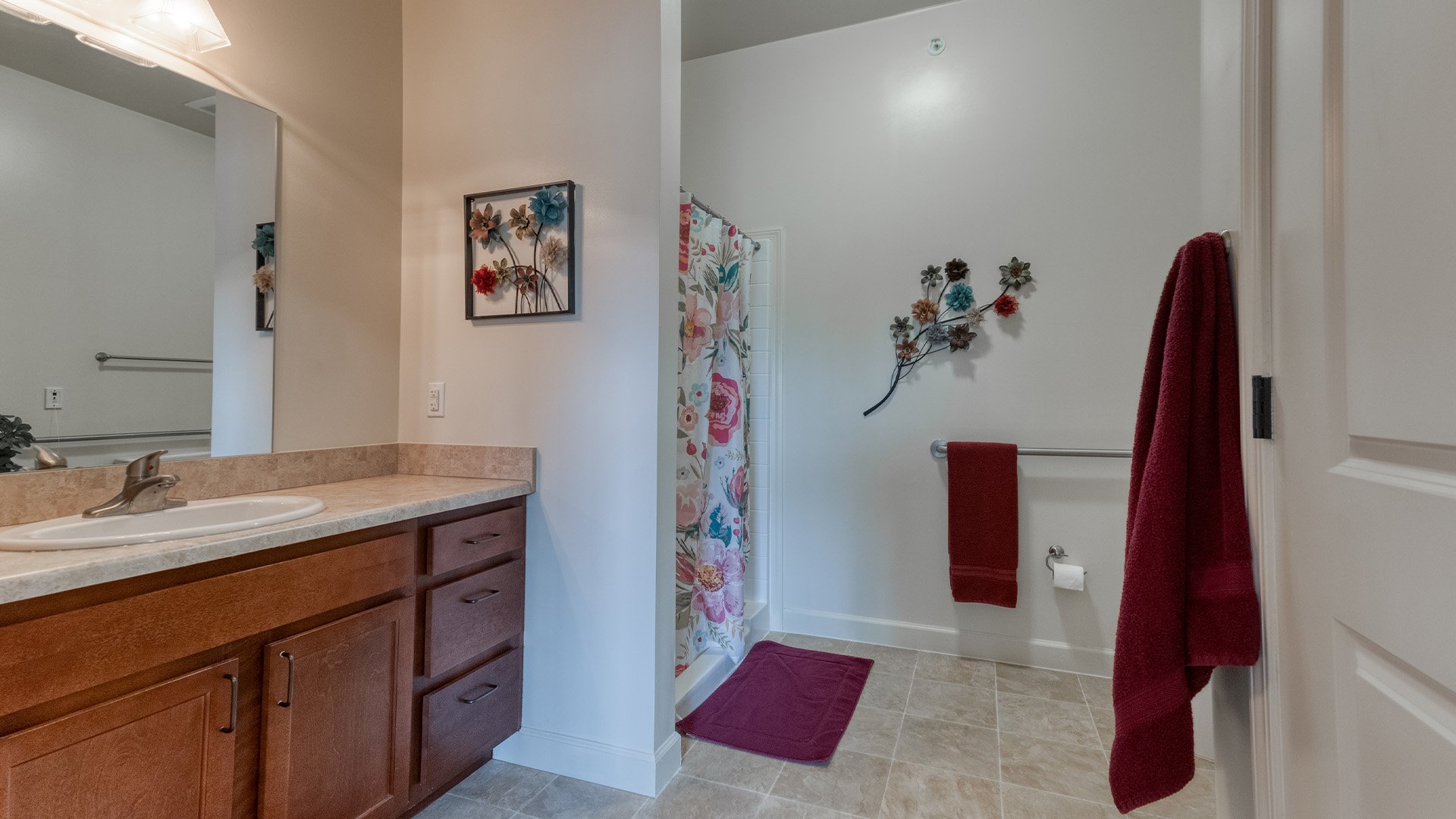 An accessible bathroom in a senior apartment at Cedarhurst of Columbia, featuring safety rails and a roll-in shower