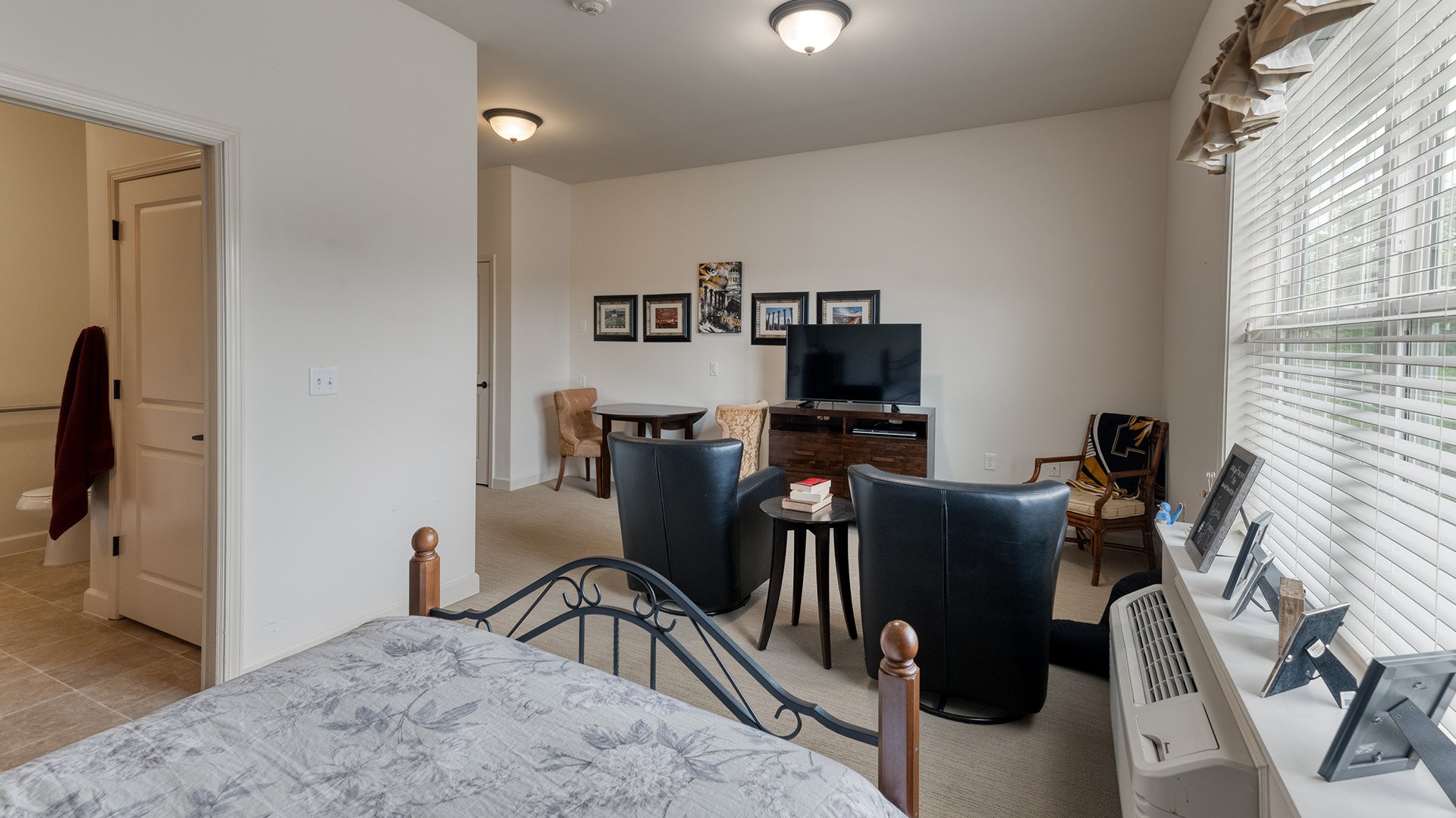 Living room and kitchenette of an apartment at Cedarhurst of Columbia, featuring accessible layouts and senior-friendly features