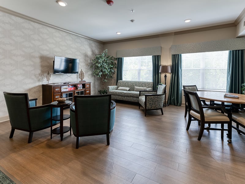 A welcoming common area at Cedarhurst of Columbia, featuring ample seating and a television, perfect for relaxation or watching programs