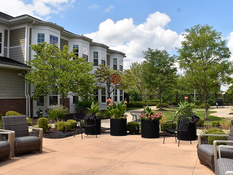 Outdoor green space at Cedarhurst of Des Peres with paved walking paths and raised garden beds