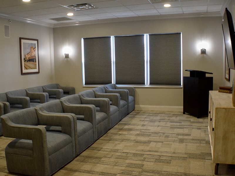 A comfortable and accessible movie theater at Cedarhurst of Des Peres, featuring a large screen and plush seating for residents' enjoyment