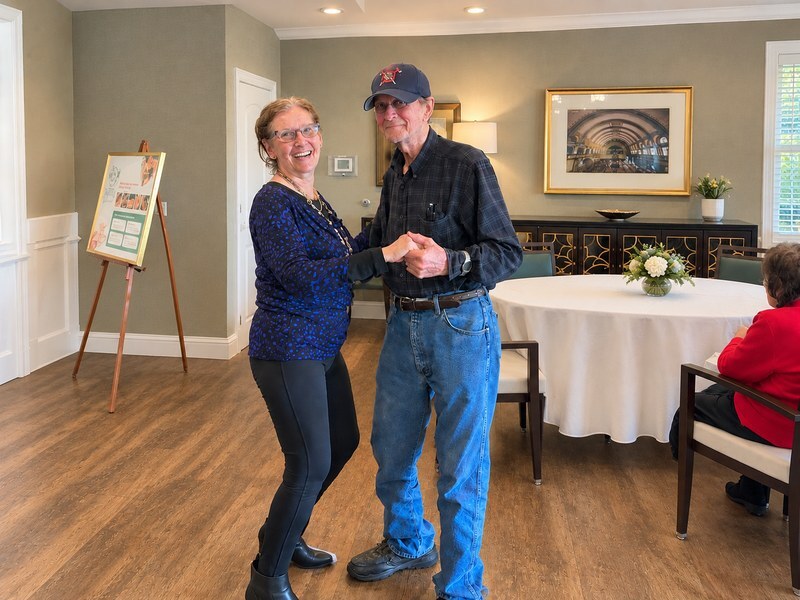 Senior living community resident dancing with a partner in the dining room.