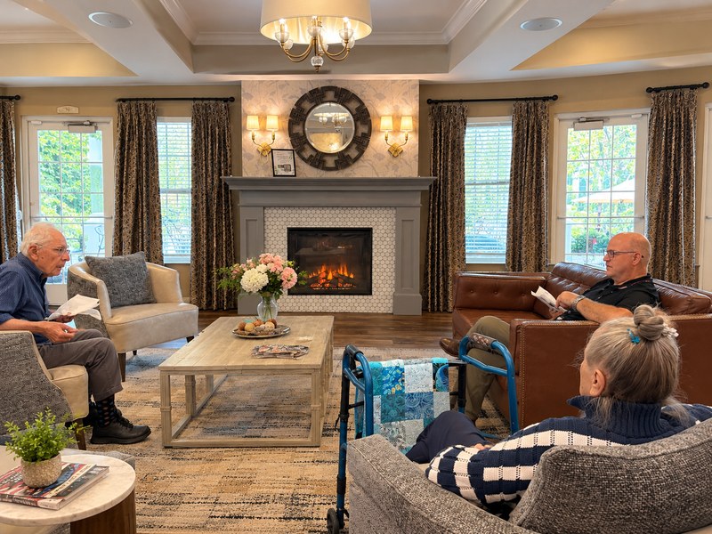 Senior living residents gathering by the fireplace in a welcoming common area.