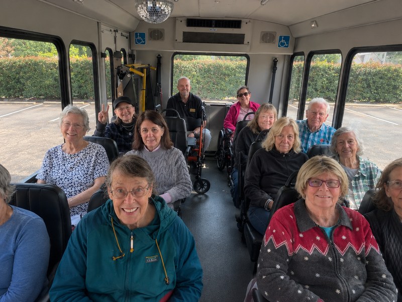 Senior living residents seated together on the community bus before a group outing.