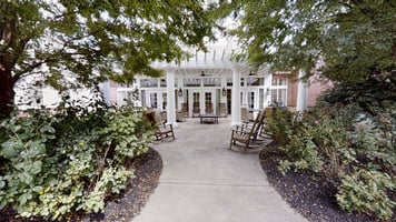 Outdoor green space at Cedarhurst of East Louisville with paved walking paths, a wooden pergola, and covered seating