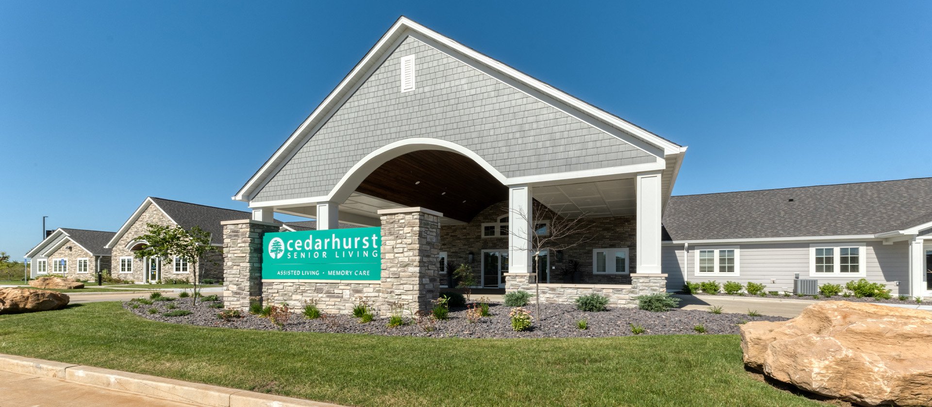 An inviting view of the Cedarhurst of Farmington senior living community from the outside, complete with the main building and its distinctive sign