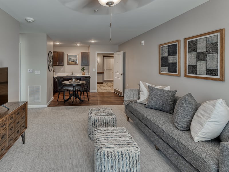 An apartment living room and kitchenette featuring accessible layouts and senior-friendly features at Cedarhurst of Farmington