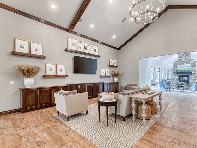 A spacious and inviting common area at Cedarhurst of Fort Wayne, designed for connection with comfortable seating, a cozy fireplace, and a television for residents across all living options