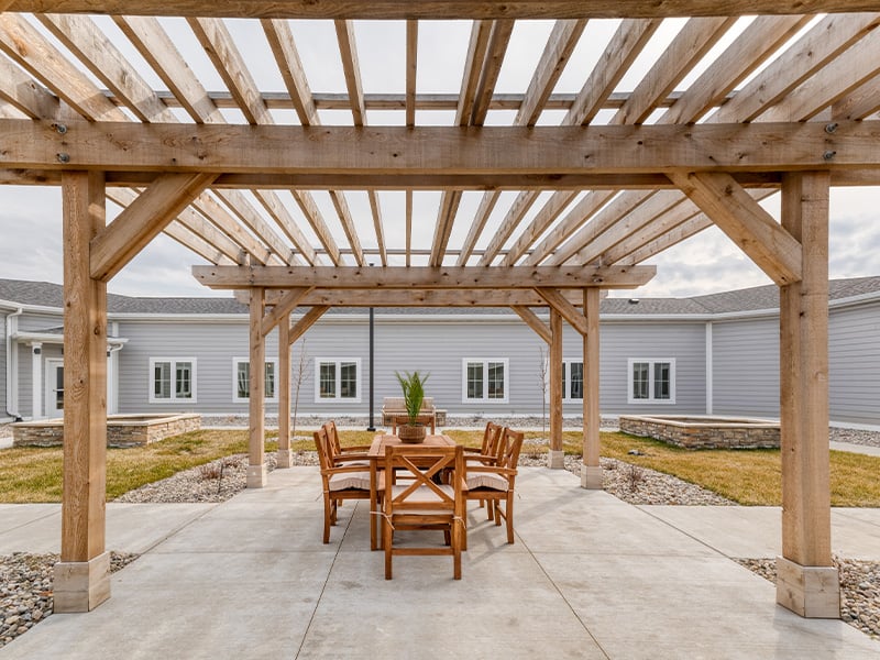 Residents at Cedarhurst of Fort Wayne can outdoor patio space with a wooden pergola, featuring conversational seating and fireplace