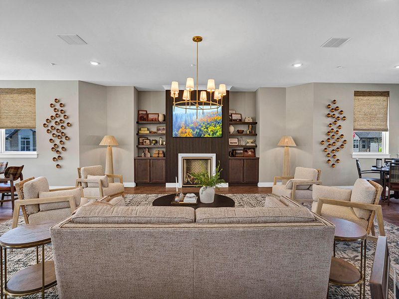 A welcoming fireplace lounge at Cedarhurst of Frankfort, offering a TV and built-in shelving for independent living residents to relax and unwind
