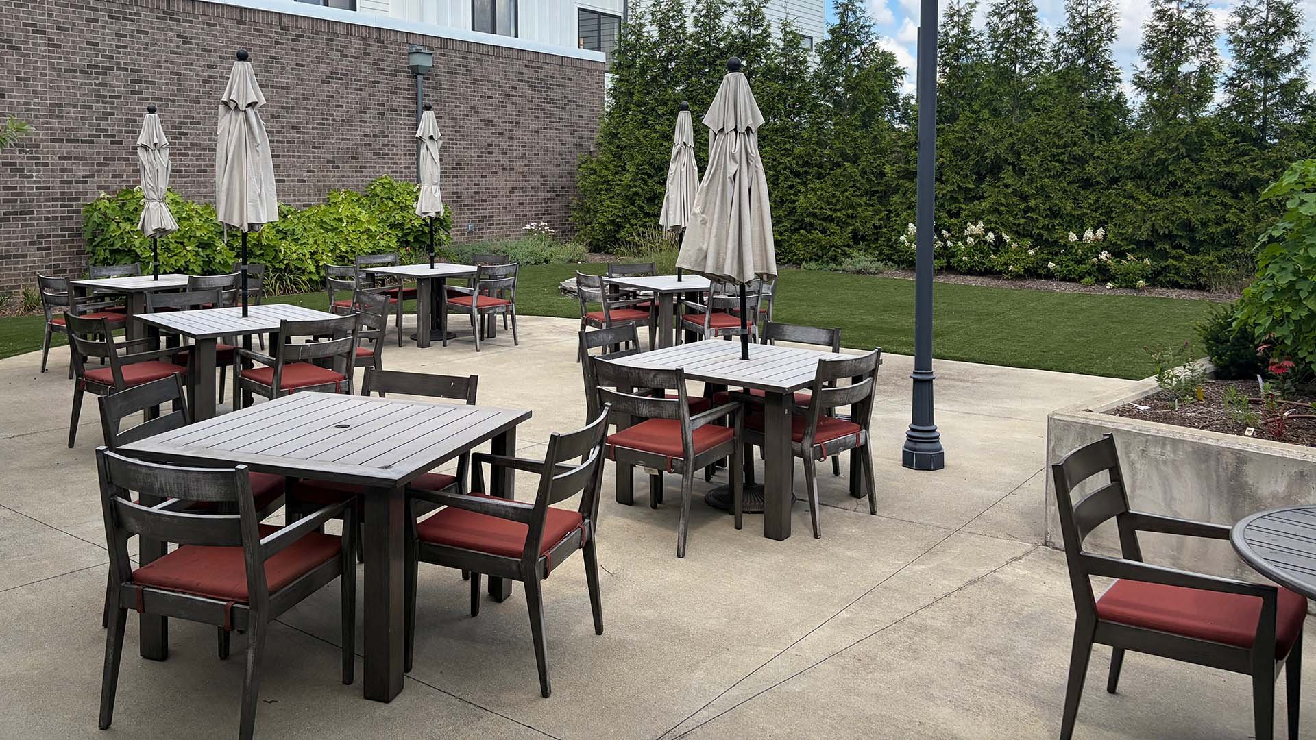 An inviting outdoor area at Cedarhurst of Hamburg, showing lush green spaces, paved paths, and a patio.