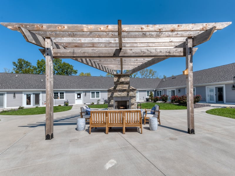 An inviting outdoor patio space with a wooden pergola with fireplace at Cedarhurst of Lebanon senior living community.