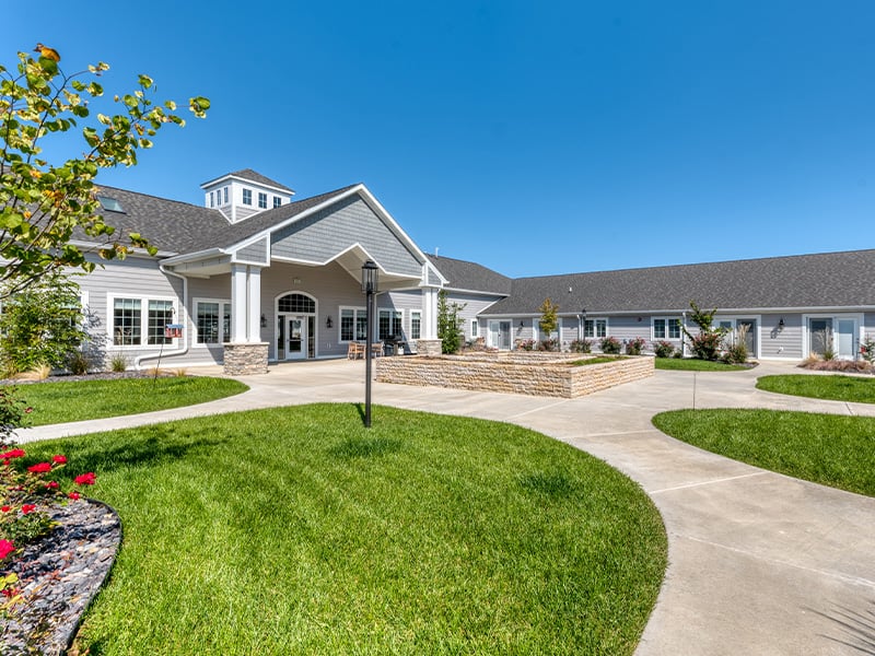 Outdoor courtyard area at Cedarhurst of Lebanon with paved walking paths, raised garden beds, and several entrances into the community.