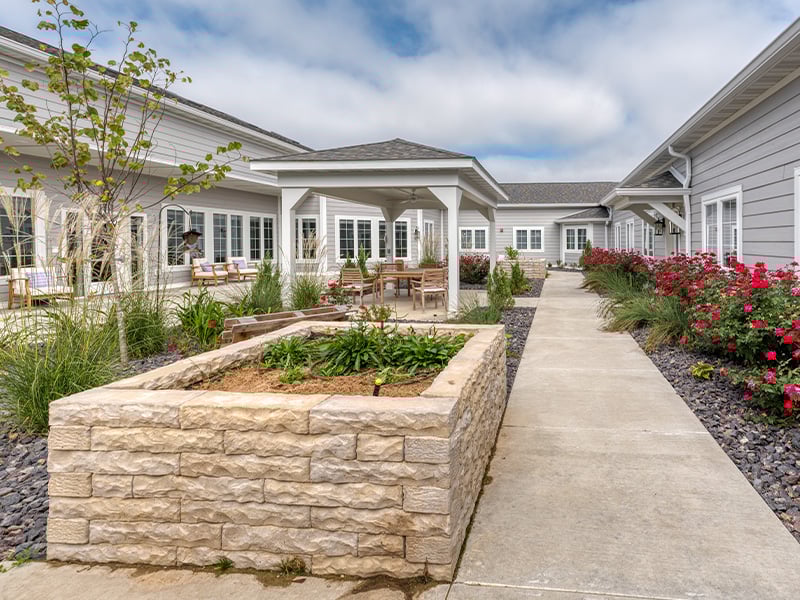 Outdoor green space at Cedarhurst of Lebanon with paved walking paths and raised garden beds.