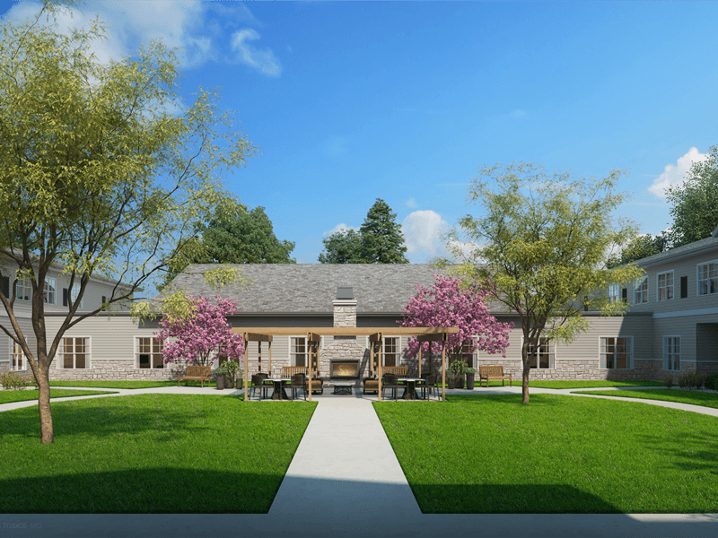 An inviting outdoor patio space with paved walking paths, comrtable seating and a fireplace at Cedarhurst of Manhattan senior living community