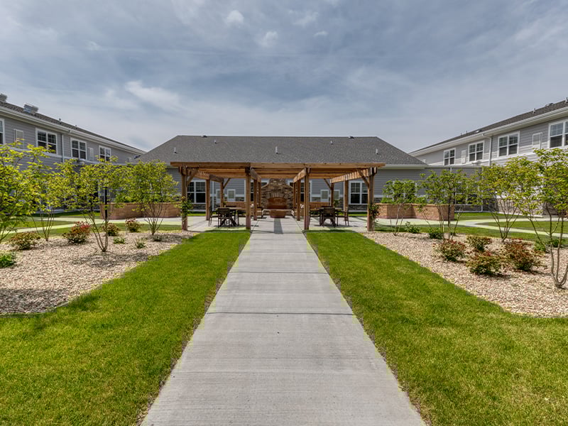 Outdoor green space at Cedarhurst of McHenry with paved walking paths and raised garden beds.