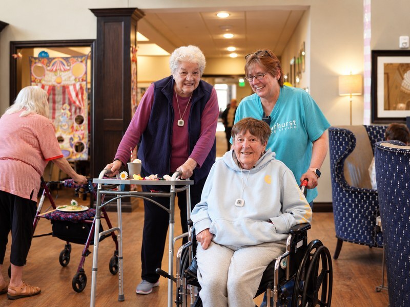 Senior living residents and a team member smiling together at an indoor celebration.