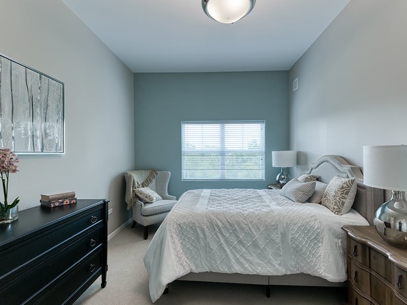 Cedarhurst of Naperville: A cozy and well-appointed senior apartment bedroom for residents.