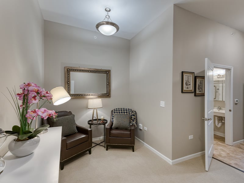 An apartment living room and kitchenette featuring accessible layouts and senior-friendly features at Cedarhurst of Naperville.