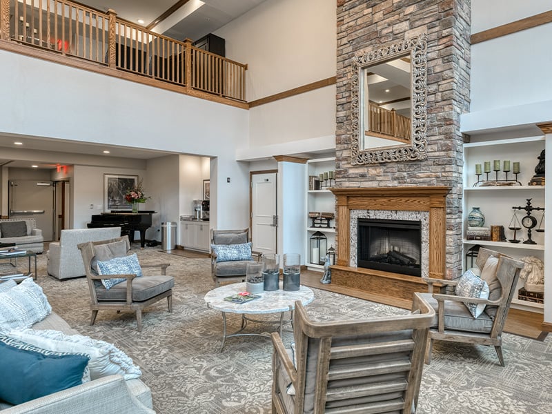 Cedarhurst of Naperville residential common area with a comfortable seating, a fireplace, and a piano.
