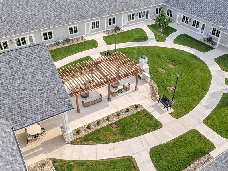 An inviting outdoor patio space with a wooden pergola with fireplace at Cedarhurst of Newburgh senior living community.