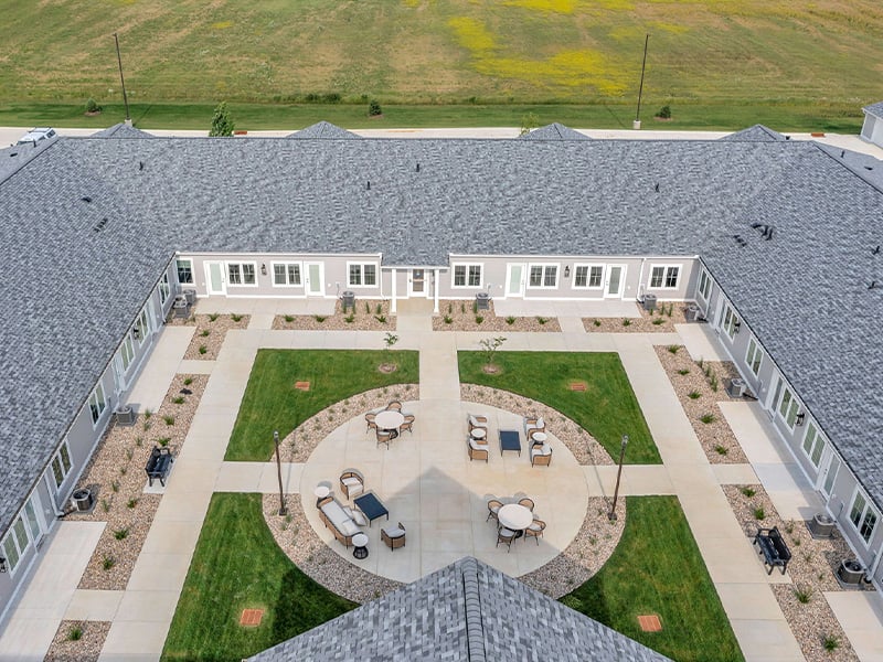 Outdoor courtyard space at Cedarhurst of Newburgh with paved walking paths and comfrtable seating.