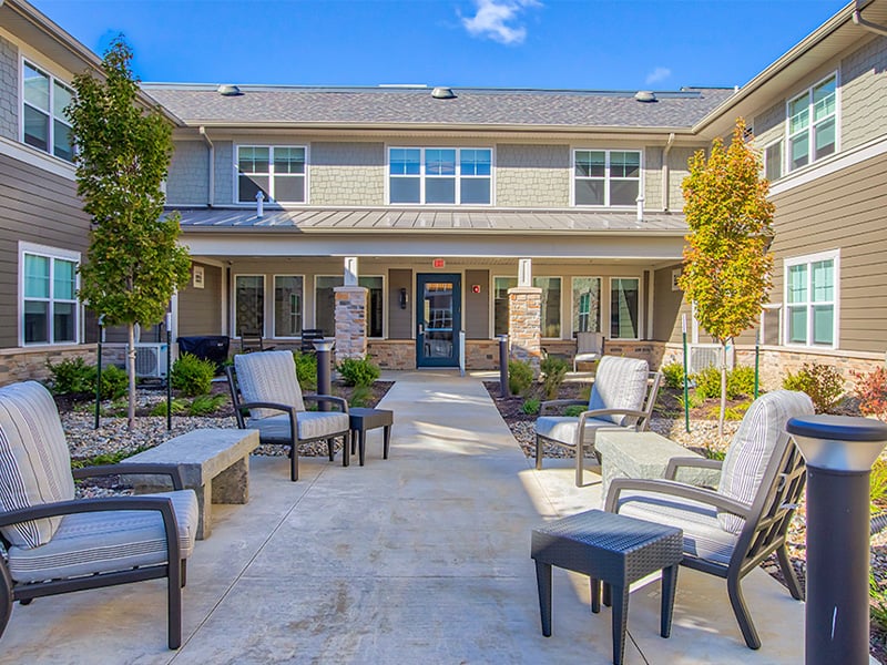 Outdoor green space at Cedarhurst of O'Fallon with paved walking paths and comfortable seating