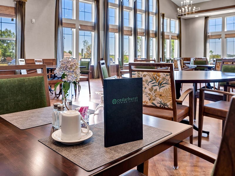 A spacious and bright dining room at Cedarhurst of Shawnee, offering comfortable seating for meals