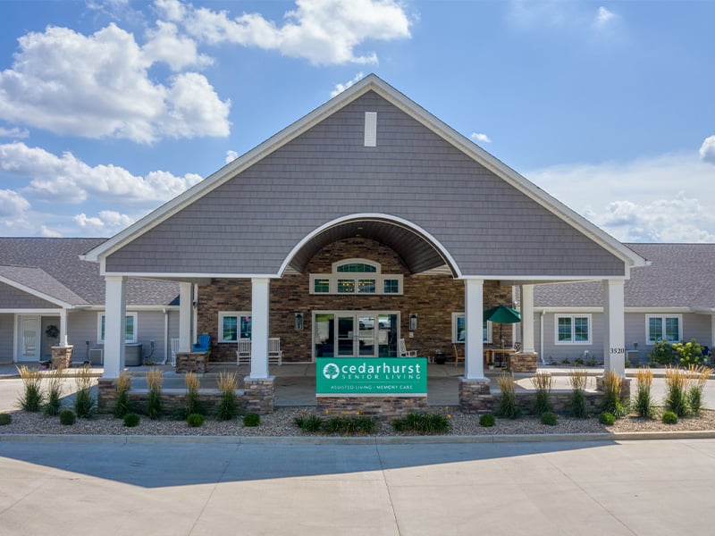 An inviting view of the Cedarhurst of Springfield, IL senior living community from the outside, complete with the main building and its distinctive sign