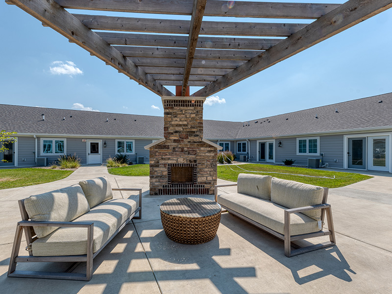 An inviting outdoor patio space with a wooden pergola with fireplace at Cedarhurst of Springfield, IL senior living community