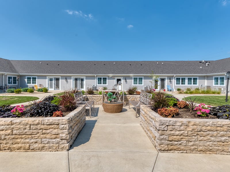 Outdoor green space at Cedarhurst of Springfield, IL with paved walking paths and raised garden beds