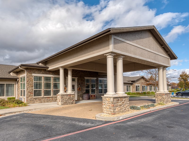 An inviting view of the Cedarhurst of Springfield, MO senior living community from the outside, complete with the main building and its distinctive sign