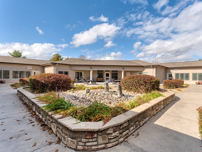 Outdoor green space at Cedarhurst of Springfield, MO with paved walking paths and raised garden beds