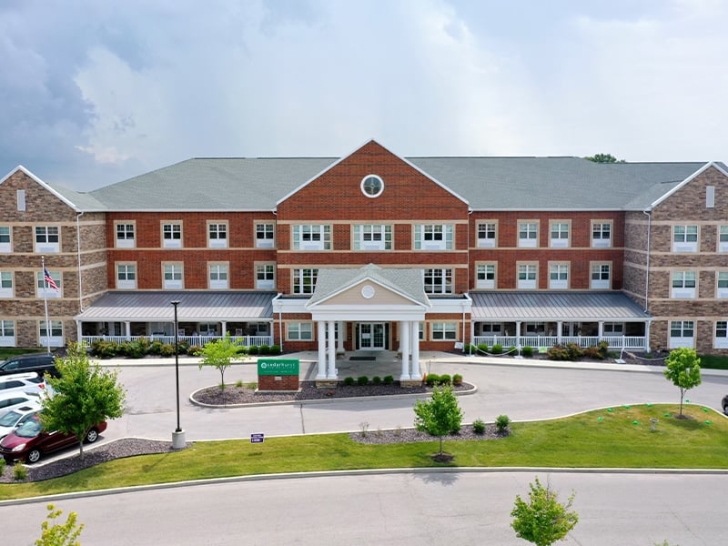 An inviting view of the Cedarhurst of St. Charles senior living community from the outside, complete with the main building and its distinctive sign