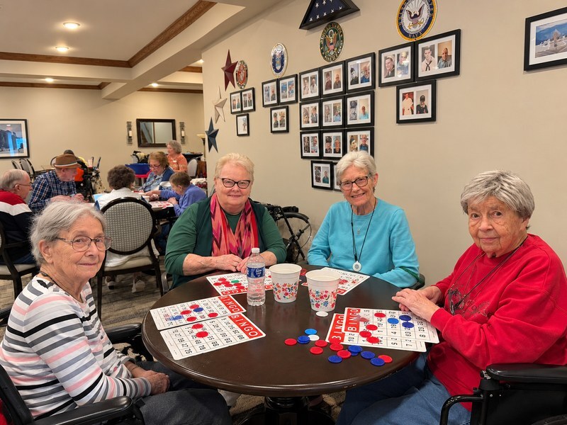 Assisted living residents playing bingo together in a senior living community activity room.