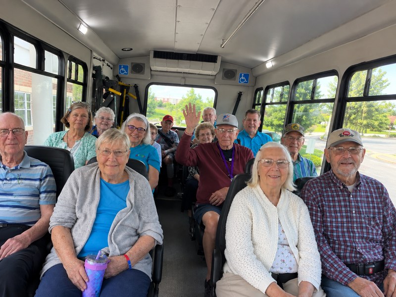 Senior living residents seated together on the community bus before a group outing.