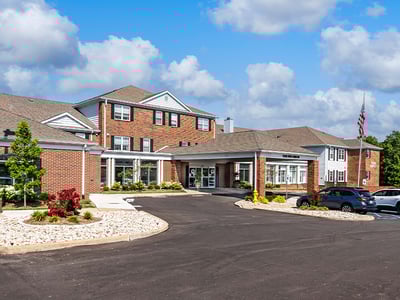 An inviting view of the Cedarhurst of Tesson Heights senior living community from the outside, complete with the main building and its distinctive sign