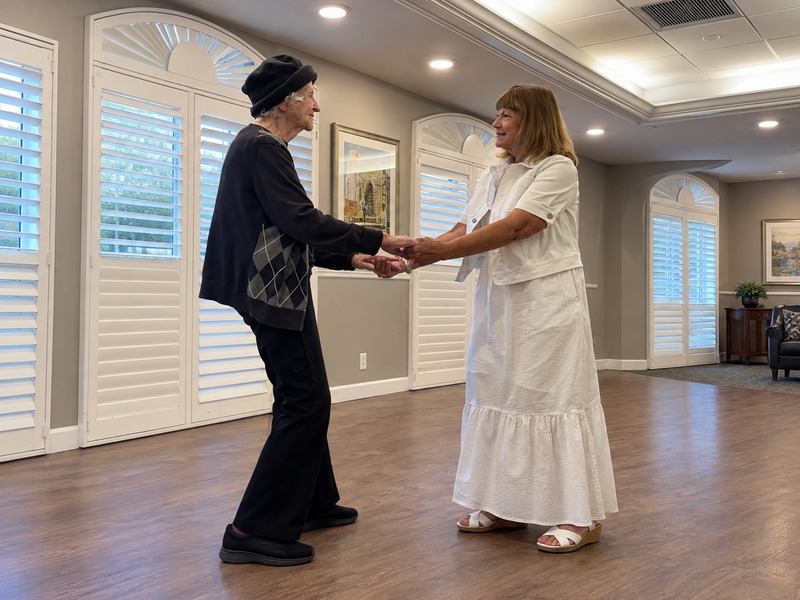 Assisted living resident dancing hand in hand with a partner at Cedarhurst of Tesson Heights