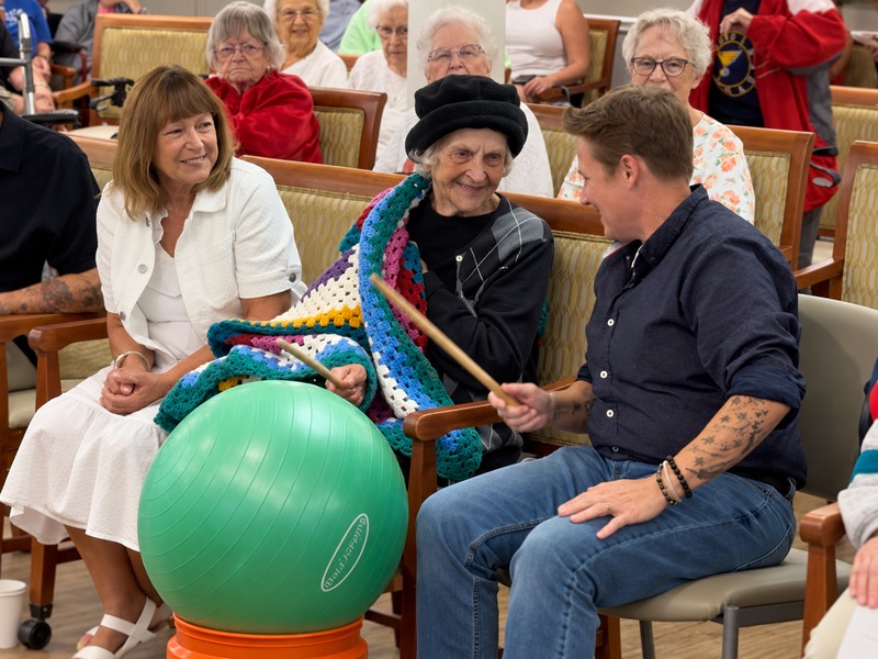 Residents enjoying a drumming class with drumsticks and exercise balls at Cedarhurst of Tesson Heights assisted living community
