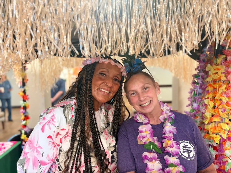 Resident and team member smiling together at a festive celebration at Cedarhurst of Tesson Heights assisted living community
