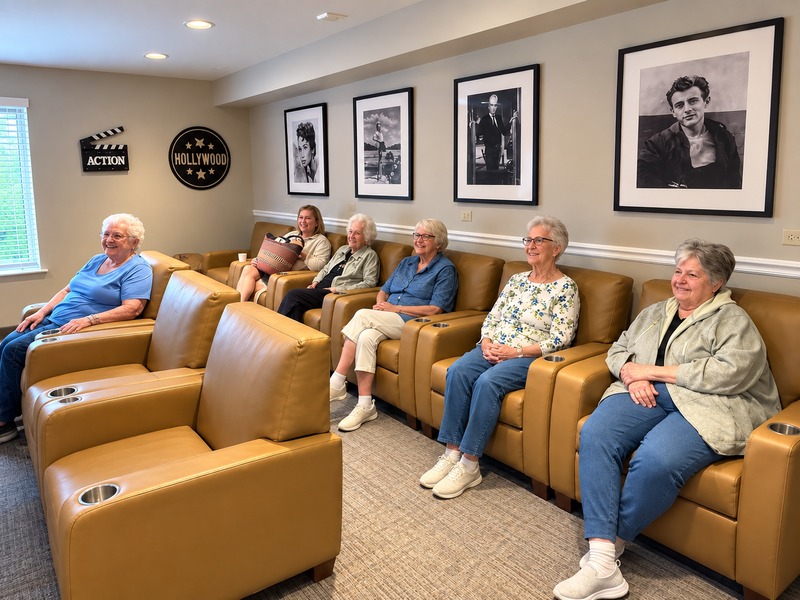 Residents relaxing in leather recliners in the Hollywood-themed movie theater at Cedarhurst of Tesson Heights senior living community